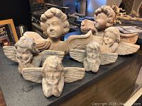 Six paper mache angels painted to resemble stone, showing various sizes and wing details.