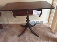 Front angle showing full extended length of drop leaf table and cast claw feet.