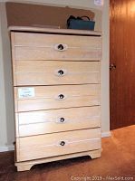 Front view of oak dresser showing five drawers with metal pulls and a label.