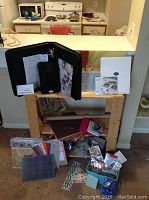 Wide view of scrapbook supplies including album, papers, embellishments, and tools arranged on and below a wooden table