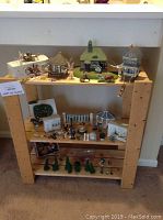Full display of Department 56 village buildings, figurines, animals, and accessories on wooden shelving.