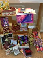 Photo showing an assortment of gift wrapping supplies including rolls of gift wrap, tissue paper, bows, ribbons, and decorative gift boxes arranged on a shelf and floor.