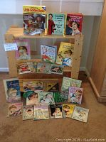 Full display of children's books including Celebrating Little Golden Books and several Eloise Wilkin illustrated titles shown on wooden shelf and floor.