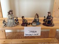 Four Yesterdays Child collectible figurines arranged on a wooden bench, showing all figures in one view.