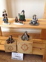 Four Dollstone Collection figurines arranged on wooden shelves with two still on their original boxes.