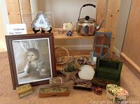 Wide view of lot showing multiple decor items such as Nippon dish, kettle, framed art, pencil boxes, and small figurines on shelves and ground