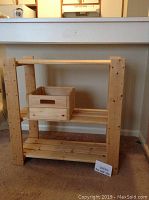 Natural unfinished pine shelving unit with three shelves shown front on under a white counter. Includes a matching pine wooden box on the middle shelf.