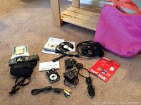 Lot of three cameras, including Canon, Olympus, and Vivitar with accessories including cords, chargers, batteries, memory cards, and carrying cases shown on carpeted floor.