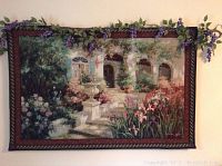 Front view of hanging tapestry showing garden scene with flowers, fountain, and stone path.