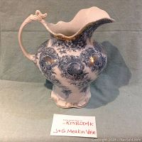 Full side view of antique pitcher showing ornate blue floral and scroll designs and gold accents.