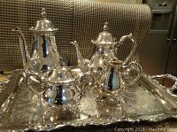Photo of the complete silver plated tea set on an ornate tray showing all five pieces - coffee pot, teapot, sugar bowl, creamer, and tray.