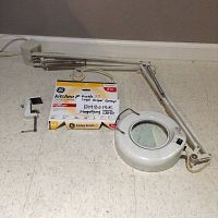 Full view of the lamp laid on the ground with clamp and box of extra GE circular fluorescent bulb