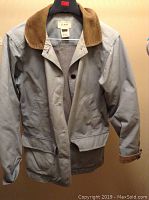 Full front view of L.L. Bean field coat in gray with brown corduroy collar, button and zipper closure, pockets, and adjustable cuffs.