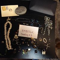 Full lot view showing assortment of necklaces, earrings, rings, brooches, pendants on a dark surface