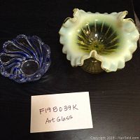 Photo showing both glass art pieces: yellow-white ruffled vase and blue swirl dish with sign 'F198039K Art Glass'