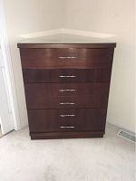 Front view of a dark brown wooden 4 drawer dresser with modern silver handles and glass top protector.