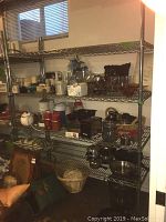 Full view of assembled chrome wire shelving unit loaded with various kitchen items against basement wall.