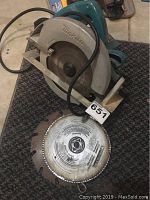 Makita circular saw lying flat showing blade and attached power cord.