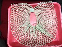 Retro beaded collar laid flat on a red satin background showing the full net pattern and button closure.