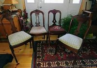 Four antique walnut Rococo style dining chairs arranged in a row with varied upholstery fabrics, set on a patterned rug in front of a window.