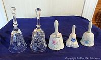 Five collectible bells including two crystal with engraving and pinwheel cut, three ceramic floral decorated bells, one marked Venezuela.
