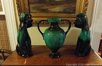 Photo of Blue Mountain Pottery vase centered with two tall dog figurines flanking it on a wooden surface, showing color and general shape.