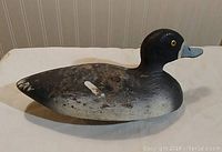 Side view showing the profile of the carved wooden duck with worn paint and detail on the beak and eyes.