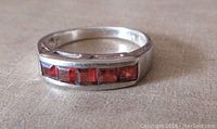Front top view showing five square garnet stones channel-set into a sterling silver band with smooth polished finish.