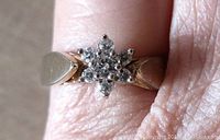 Close-up of the floral cluster ring on finger showing clear stones and silver band.