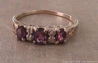Front view showing three oval purple amethysts and two clusters of small round diamonds