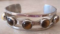 Close up of the silver bangle with five tiger eye stones set in bezels.