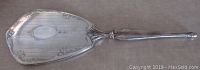 Front side of the silver hand mirror showing embossed floral decoration and decorative handle with no monograms.