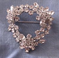 Front view of the heart-shaped brooch showing clear Swarovski crystals arranged in floral clusters with round and marquise cuts on rhodium plated setting.