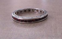 Close-up image of the sterling silver ring profile showing the channel set garnets and engraved scroll design along the band.