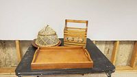 Four decorative wood items arranged on a black table: wooden tray, hanging mail holder, woven food net, and lazy susan.