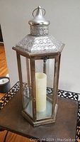 Front view of the large hexagonal Pier One flameless candle holder with perforated metal top and wooden-framed glass panels, containing a white flameless candle.