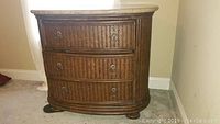 Photo of one island style night stand showing carved woven drawers and granite top