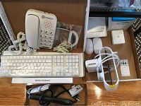 Overview of all items in the lot: Southwestern Bell phone, two Apple wireless keyboards, two wireless mice, surge protector, extension wire, and chargers