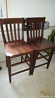 Two Pottery Barn wooden bar chairs side by side showing slatted backs and seats.