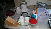 Lot contents visible on white table showing ice cream maker, mugs, bakeware, and other kitchen goods
