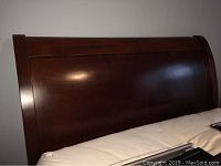 Close-up of Pottery Barn full size sleigh style headboard in dark wood finish.