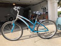 Side view showing entire blue and white womens Huffy AirRide bike with visible front suspension and kickstand.