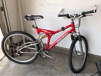 Side view of full red mountain bike showing frame, tires, seat, and pedals