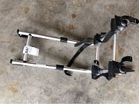 Aluminum bike rack shown on concrete floor, visible with black plastic clamps and straps, used condition