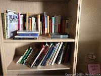 Two shelves of assorted used hardcover and softcover books including titles like 'The Divine Matrix' by Gregg Braden.