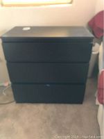 Front view of the black 3 drawer dresser showing drawer fronts and base.