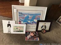 Full view of all items included in the lot showing five art pieces and the book on wood floor.