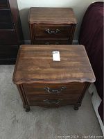 Two matching wooden nightstands placed in a bedroom, showing front and top views with visible surface wear.