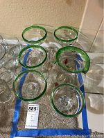 Overhead view of 5 margarita glasses arranged on carpet, showing thick green rims and clear glass bodies.