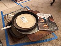 Set of baking pans, pizza stone, racks, splatter covers and two recipe booklets with visible use wear and staining.